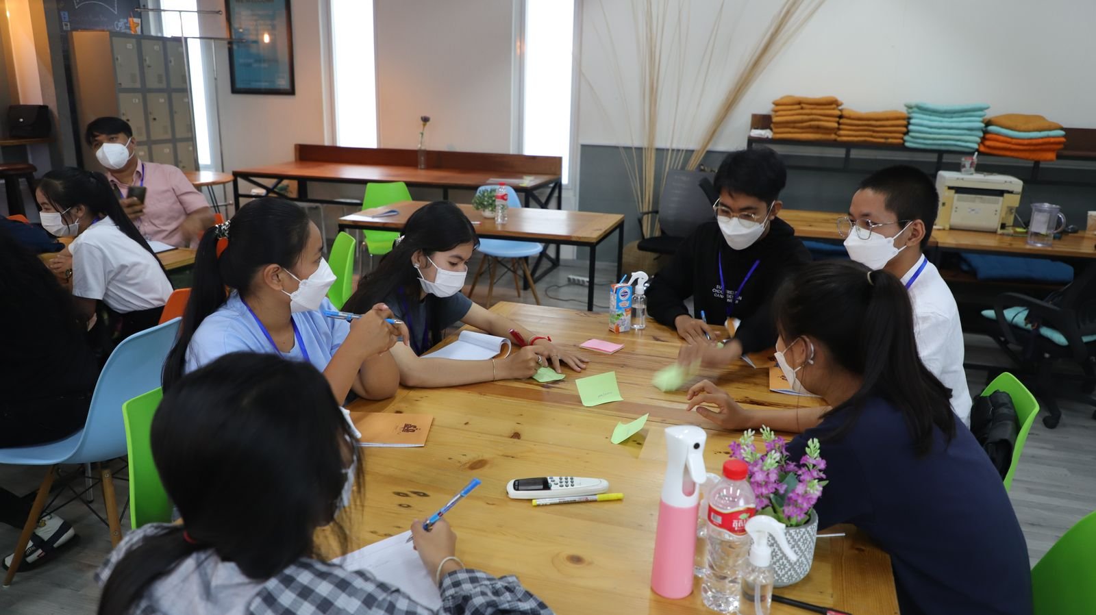 A small group huddled around a table covered in sticky notes during a peer-learning exercise