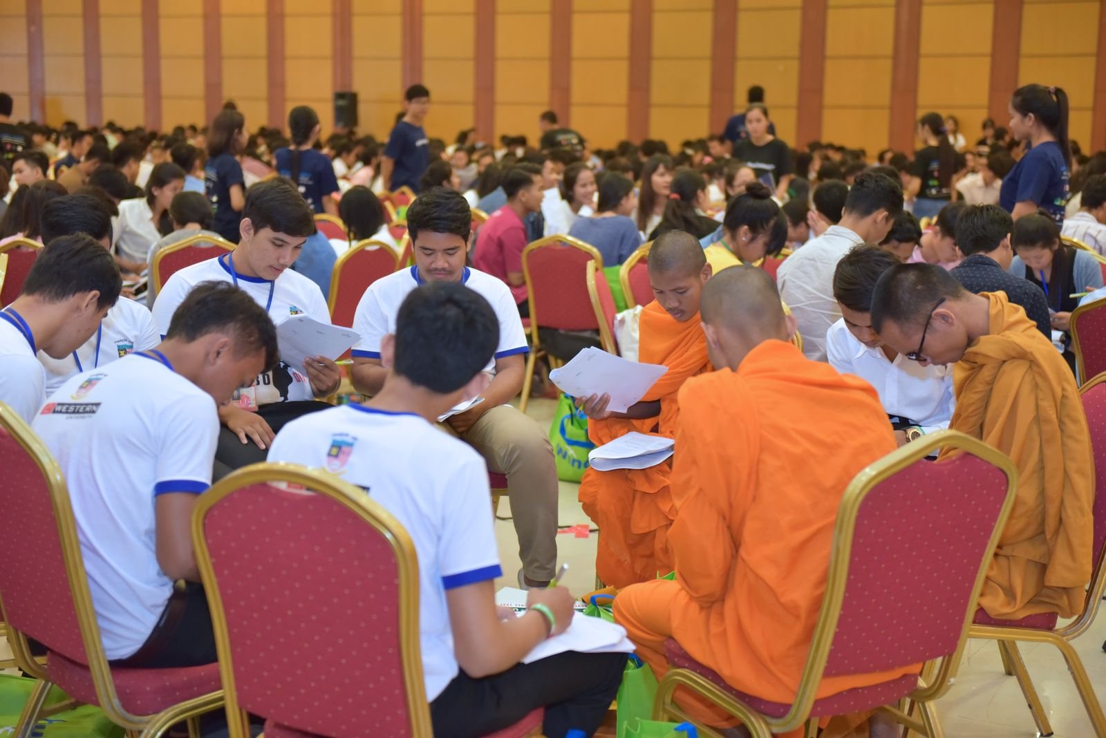 A very large conference hall full of participants, including Buddhist monks, working through ABL exercises